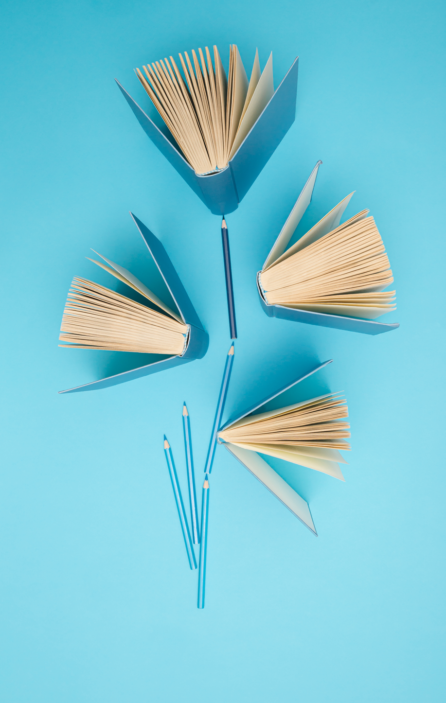 Pastel blue books and pencils on bright blue background